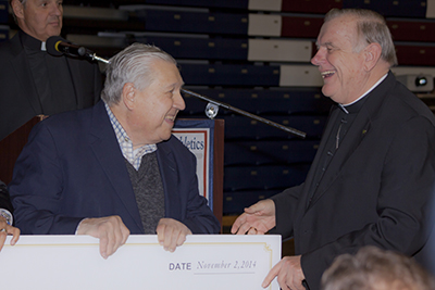 To the right, Archbishop Thomas Wenski receives a check with a 500,000 dollar donation from businessman Arthur H. Hertz during the 6th Annual Stone Crab Dinner for Athletics. The event took place November 2nd at St. Thomas University.  The donation will help establish the Arthur H. Hertz Endowed Professorship in Sports Tourism.