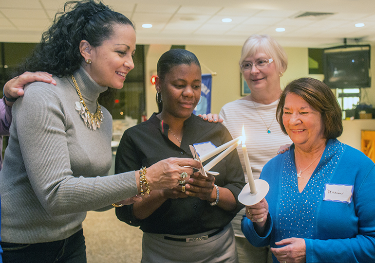 New members of St. Gregory Women's Guild, from left, Angelina Miller, Marie Laurat and Marion Zegar light their membership candles as member Diane Cantamesa puts her hand on Laurat's and Zegar's shoulders.