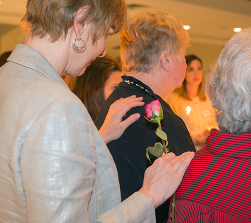 Old and new members are bound by touch and roses as St. Gregory Women's Guild inducts new members during a candlelight ceremony at their January meeting.