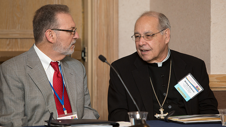 Bishop Felipe Estevez of St. Augustine, right, talks with Raul Hernandez, citizenship coordinator, New Americans Campaign, for Catholic Legal Services of the Archdiocese of Miami, on Feb. 12, during a workshop on caring for refugees held at the Jacksonville Hyatt Riverside Hotel. The event was sponsored by the Florida Department of Children and Families.