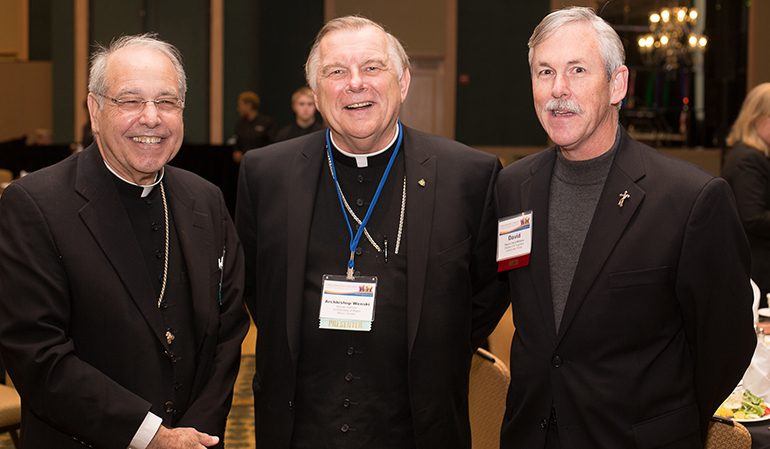 Bishop Felipe Estevez, left, and Deacon David Williams, right, of the Diocese of St. Augustine, pose with Miami Archbishop Thomas Wenski Feb. 12 at the Jacksonville Hyatt Riverside Hotel. Both bishops spoke at the 2015 Refugee Services Consultation sponsored by the Florida Department of Children and Families.