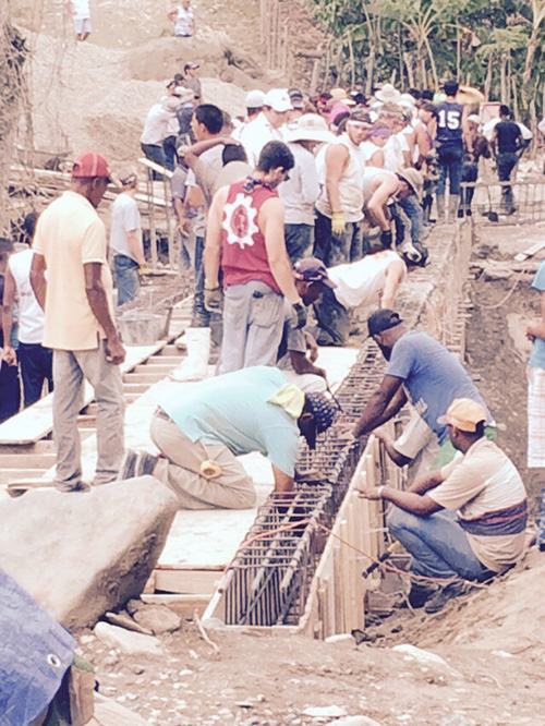 Belen Jesuit students work side by side with men from the village of El Puerto in the Dominican Republic to build a bridge that will be used by the villagers to transport agricultural products and allow students easy access to schools in the neighboring villages.