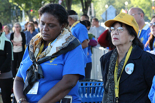 Las peregrinas Margaret Noailles (izquierda) y Ann Tan (derecha) reflexionan mientras se ve la Misa de canonización de Fray Junípero Serra en una pantalla gigante, en el National Mall.