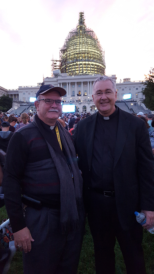 Mons. Terence Hogan (derecha) con suerte encontró a los peregrinos de la Arquidiócesis de Miami en medio de la multitud, detrás del Capitolio. Aquí, él posa con el obispo Fernando Isern (izquierda) frente al Capitolio.