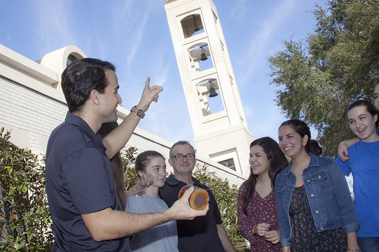 St. Mark's Youth minister Gustavo De La Fé points at St. Mark's bell tower as he holds one of two broken solenoids that were repaired. To his right are Karina Czubkowski, Scott Czubkowski, Emily Lantigua, Katherine Lantigua, and Sarah Roberge.