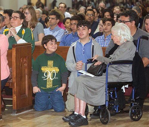 St. Theresa second grader Charlie Hernandez, 7, and brother Javier Hernandez, class of 2015 and currently attending Christopher Columbus High, sit next to their grandmother, Maria Lopez, whose five daughters graduated from St. Theresa School. Their mother, Cristina Hernandez, class of 1982, is kneeling at left.