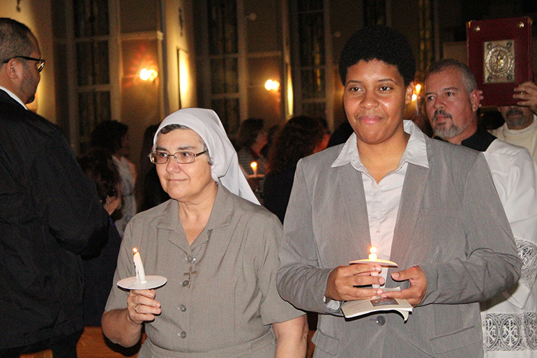 Claretian Missionaries Sister Ondina Cortes, left, director of novices in Miami, and Sister Eridania Reinoso, who made her first profession of vows during the Mass at Corpus Christi Church, carry candles during the entrance procession, representing the light of the Year of Consecrated Life.