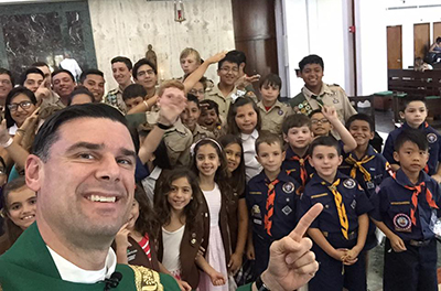 Piarist Father Rafael Capo takes a selfie with Scouts at the end of the Mass.