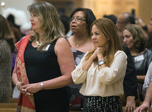 Newly-commissioned youth ministers Maxine Mitchell Alvarez and Siulin Kang from Little Flower Church, Coral Gables, watch as Archbishop Wenski processes out of the cathedral after Mass.