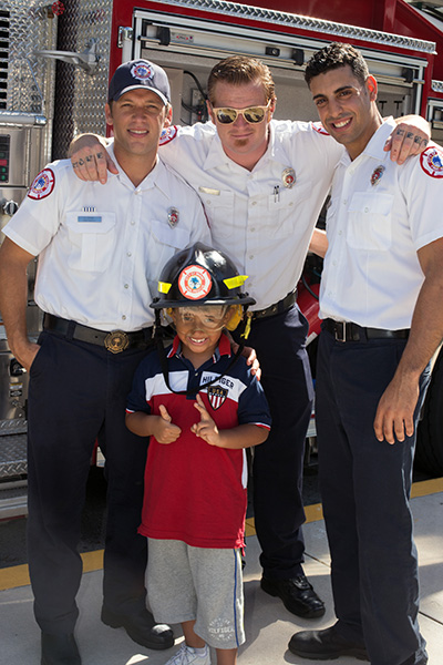 Firefighters Victor Cobian, Kellan Covalt and Eddie Marrero pose for a photo with Douglas Quintero, 3, outside St. Hugh Church on the 15th anniversary of 9/11.