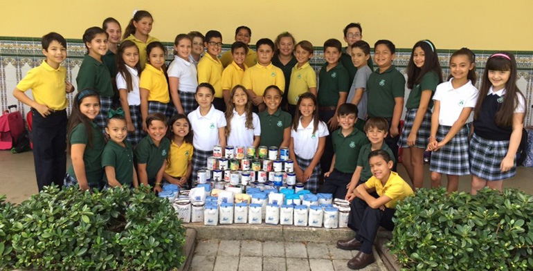 St. Kevin fourth graders pose with their contribution: sugar and canned milk.