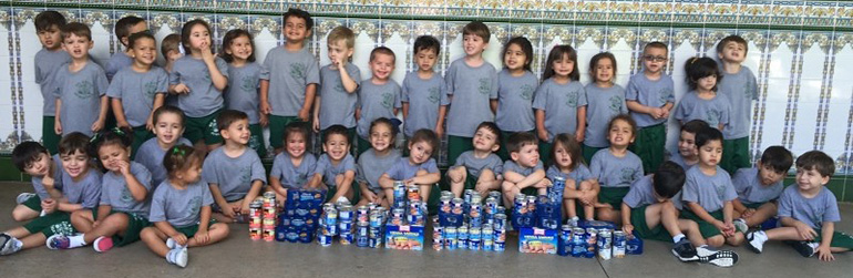 St. Kevin pre-k students pose with their contribution: canned tuna and sausages.