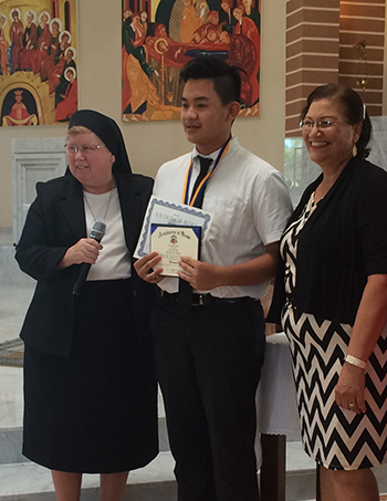 Sister Elizabeth Worley, archdiocesan chancellor for administration, presents the ADOM Virtual Catholic School diploma to high school graduate Ian Ongjoco of Holy Family Academy. At right is the school's principal, Wilma Villaronga.