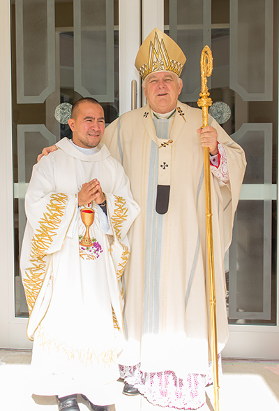 Archbishop Thomas Wenski poses for photos with newly-ordained Trinitarian Father Richard Giner in front of the recently remodeled chapel of Holy Rosary-St. Richard Church.