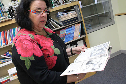 St. Andrew School Principal Kristen Hughes flips through an old year book.