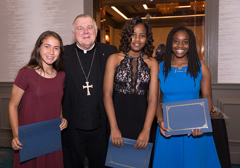 Archbishop Thomas Wenski poses with student scholarship recipients at a closing banquet for the Miami Archdiocesan Council of Catholic Women's annual convention. From left: Sabrina Sousa of Blessed Trinity School, Marie Berdelie Seide of St. Helen School in Lauderdale Lakes and Lisdrasanac Louimeus of St. James School.