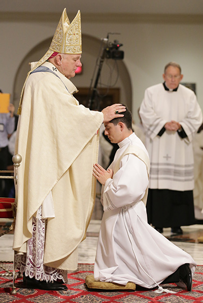 El Arzobispo Thomas Wenski le impone las manos a Alexander Rivera, ordenándolo al sacerdocio.