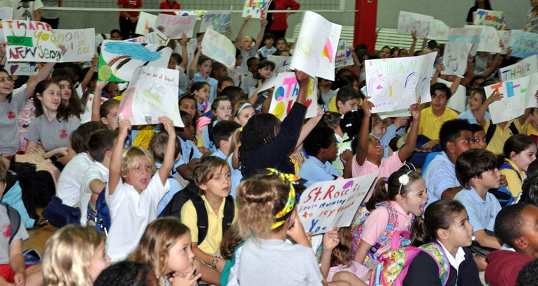 Students at St. Rose of Lima School, Miami Shores, wave a sea of posters via videoconference to thank fellow Catholic students in New Jersey.