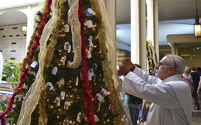 Deacon Jose Naranjo blesses a Christmas tree during a lighting ceremony at Our Lady of Mercy Cemetery in Doral.