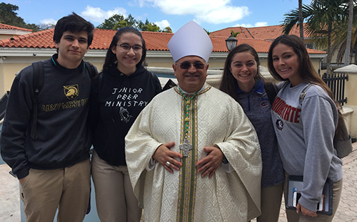 Students from Archbishop Edward McCarthy High School in Southwest Ranches pose with Auxiliary Bishop Enrique Delgado before the chrism Mass. From left: Franco Chiappori, Lindsey Millares, Bishop Delgado, Karina Czubkowski, and Makayla Sandoval. All are seniors and serve as extraordinary ministers of holy Communion at the school.