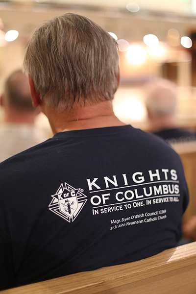 A St. John Neumann Knight of Columbus listens to the reflection before one of the mysteries of the rosary during the prayer service for immigrants held at the parish on the feast of the Assumption.