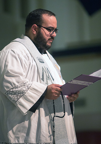 Father Matthew Gomez, parochial vicar at St. John Neumannn, reads a reflection on immigration before one of the mysteries of the rosary.