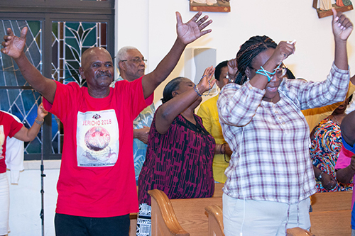 Jules Verme, far left, joins others in praying and swaying to the music during Jericho 2018 at Notre Dame d'Haiti Mission in Miami.