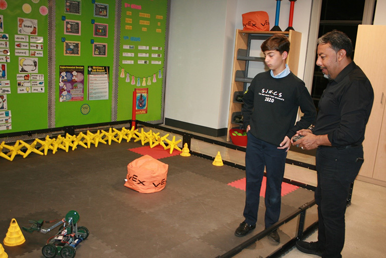 St. John Neumann eighth grade student Nicholas Fleites demonstrates the Vex robots to a guest.