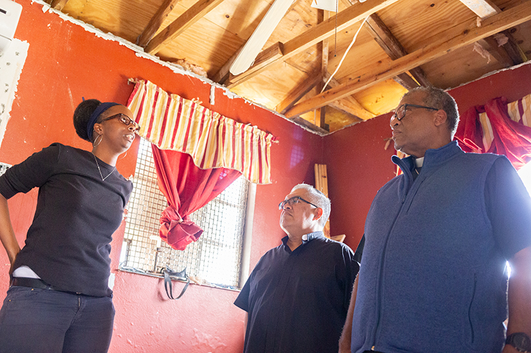 Kesheia Morris, a projects officer for the minor repairs program, discusses details of a Caritas home rehab project near Freeport, Grand Bahama, following last year's Hurricane Dorian. On the right are Msgr. Roberto Garza, board chairman for Catholic Charities Miami, board chairman for Catholic Charities Miami, and Nassau Archbishop Patrick Pinder, far right.