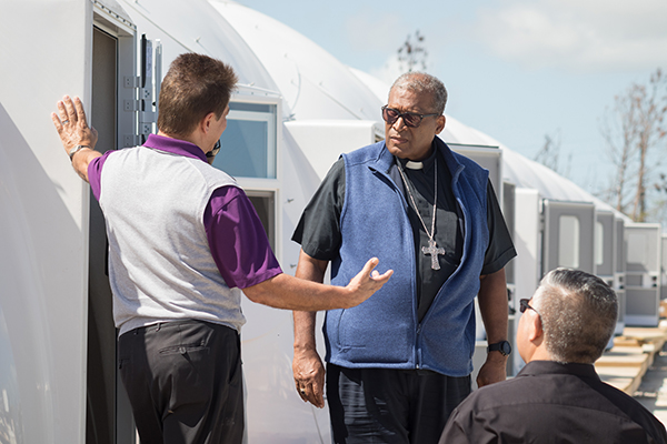 Nassau Patrick Archbishop Pinder led a small delegation of Archdiocese of Miami Catholic Charities senior staff through Nassau, Grand Bahama and Great Abaco Island Feb. 19-21, including Catholic Charities Miami CEO Peter Routsis-Arroyo, left, and Msgr. Roberto Garza, board chairman for Catholic Charities Miami. They are seen here at new temporary housing structures on Abaco.