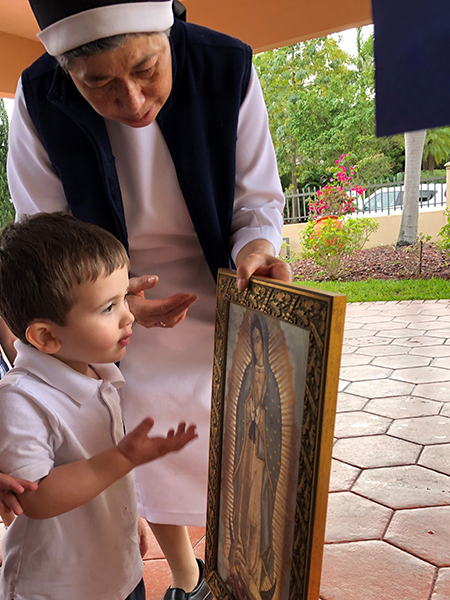 Sor María del Rosario Gutiérrez, directora de la guardería de las Teatinas, le enseña una imagen de la Virgen de Guadalupe a un niño en edad preescolar que asiste al centro.