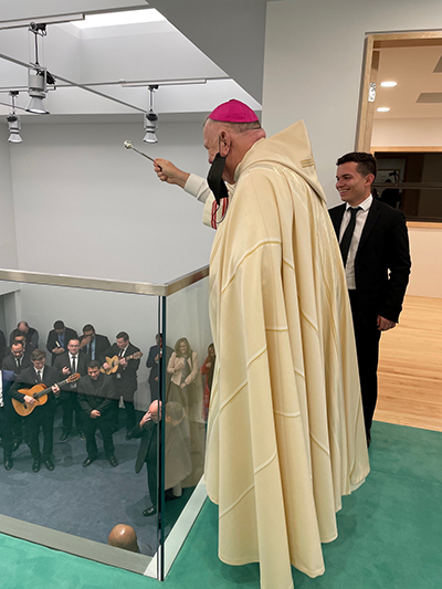 Standing on the second floor, Archbishop Thomas Wenski blesses a new building at the Redemptoris Mater Archdiocesan Missionary Seminary in Hialeah, Dec. 10, 2020.