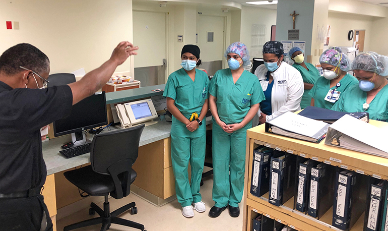 Father J. Sterling Laurent, a priest chaplain at Miami's Mercy Hospital for the past nine years, and a priest in residence at nearby St. Kieran Parish, prays with medical staff at Mercy. The chaplain's day usually begins around 7 a.m. by praying with the nurses, doctors and medical staff at the start of their morning shifts.
