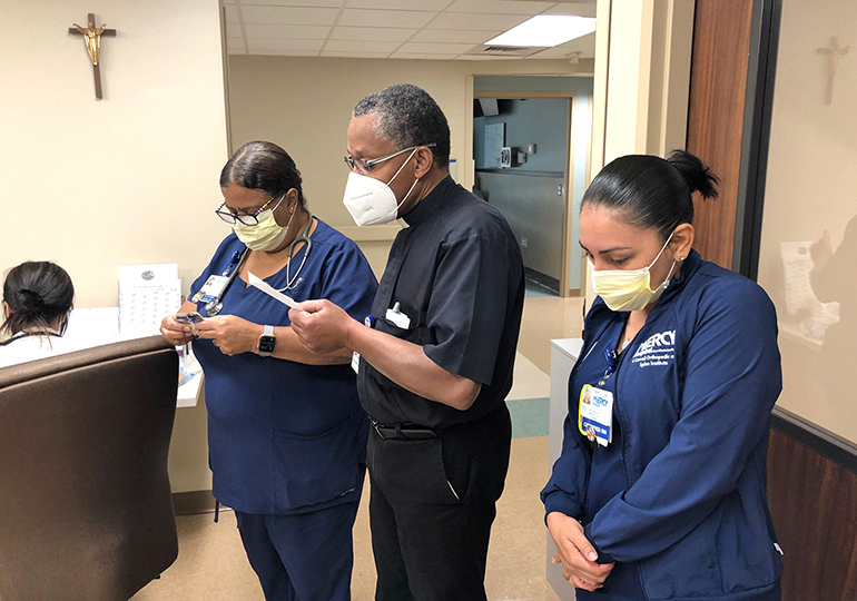 Father J. Sterling Laurent, a priest chaplain at Miami's Mercy Hospital for the past nine years, prays with medical staff at Mercy. “We gather for prayer and anything in particular they want to pray about, for their safety,” said Mike Garrido, Mercy Hospital’s vice president of mission integration.