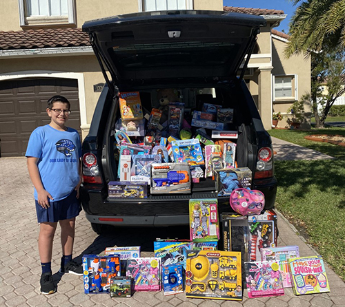 Nicholas Merchan poses with some of the more than 300 toys he and his fellow students at Our Lady of Lourdes School collected for Las Hormiguitas del Senor (God's Little Ants) in the Redland.