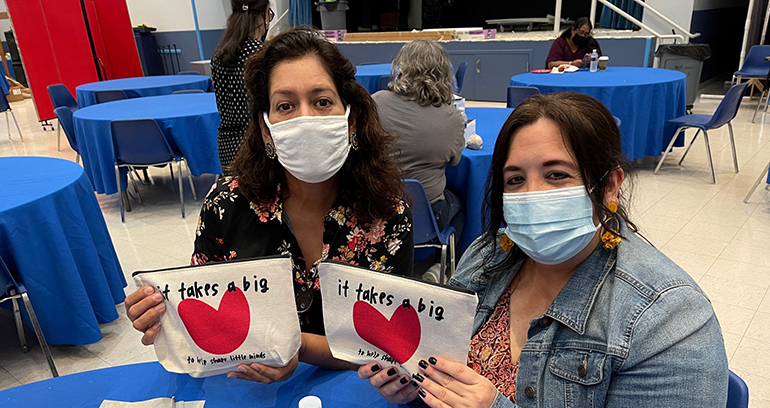 Mother of Our Redeemer teachers hold banners that read, "It takes a big heart to help shape little minds."