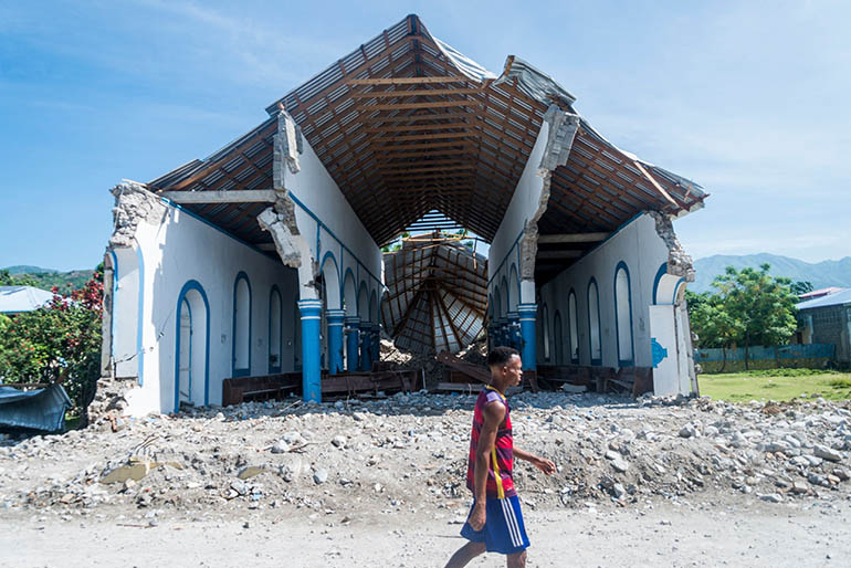 A man walks past a church destroyed during an earthquake in Les Anglais, Haiti on Aug. 14, 2021. The death toll from Haiti's powerful earthquake jumped to over 1,200 on Aug. 15, 2021, as crews desperately dug through collapsed buildings for survivors in the Caribbean nation still reeling from its president's assassination. In Les Cayes, as in other hard-hit cities on the southwestern peninsula, most of the population spent the night sleeping outdoors in front of their houses -- or what remained of them -- amid fears of new aftershocks.