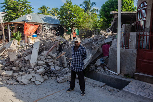 A man stands in front of his neighbor's collapsed house after a 7.2-magnitude earthquake struck Haiti on Aug. 16, 2021 in Corvalion, Les Cayes. Rescue workers have been working among destroyed homes since the quake struck on Saturday and so far there are 1,297 dead and 5.700 wounded. The epicenter was located about 100 miles west of the capital city Port-au-Prince.