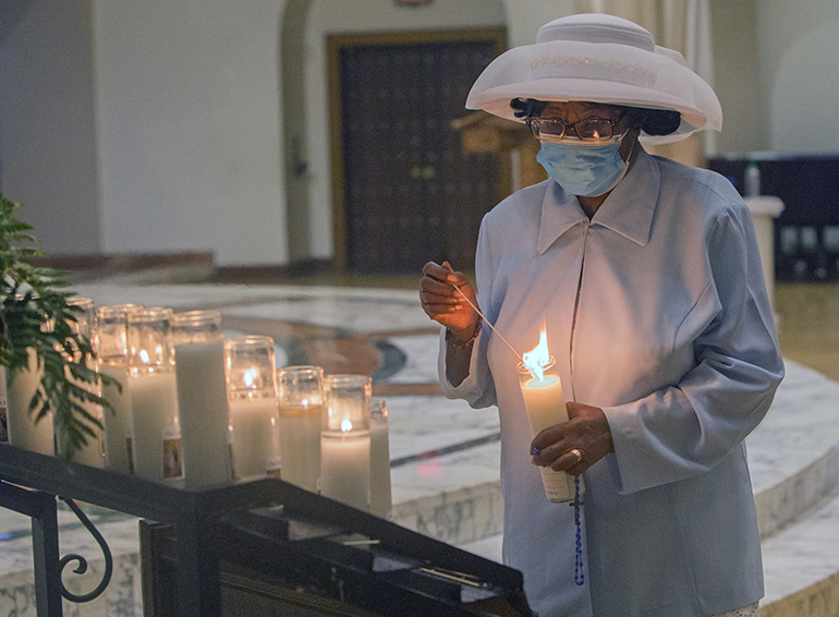 Elmira Louissant lights a candle in front of an image of Mary at St. Mary Cathedral on the feast of the Assumption, Aug. 15, 2021, a day after a 7.2 earthquake killed nearly 1,300 people in Haiti's southwestern peninsula. She was one of those in attendance at the Mass Archbishop Thomas Wenski celebrated to pray especially for the earthquake victims.