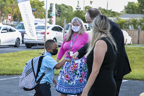 Dian Hyatt, principal, looks on as Jim Rigg, archdiocesan schools superintendent, greets a student as he arrives at St. Lawrence School for the first day of the 2021-22 school year, Aug. 18, 2021.