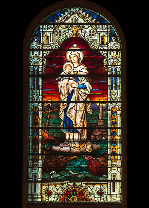 The main stained-glass window, an image of Our Lady Star of the Sea, makes a stunning visual for those making a visit or  pilgrimage to the historic Basilica of St. Mary Star of the Sea in Key West.