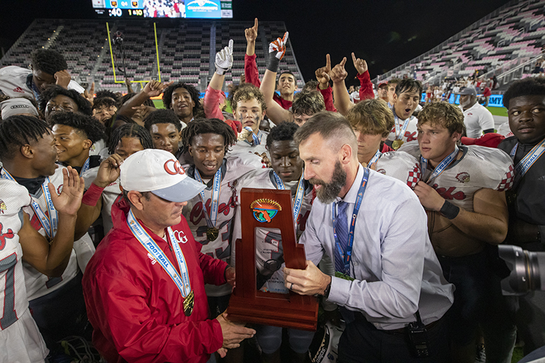 Cardinal Gibbons head coach Matthew DuBuc receives the Class 4A State Championship trophy at the conclusion of the game between Cardinal Gibbons and Cocoa Beach at DRV PNK Stadium in Fort Lauderdale, Dec. 16, 2021.