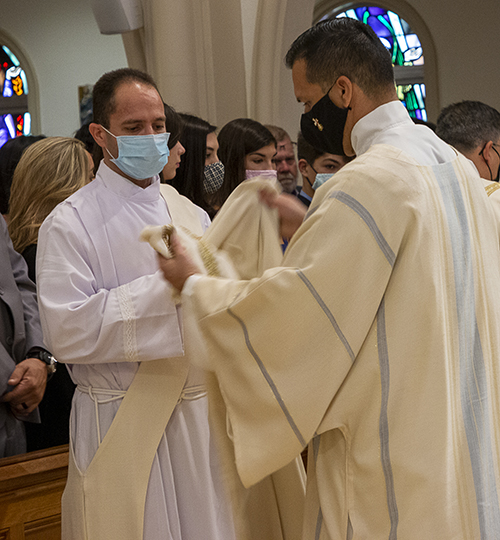 Deacon Benjamin Roa, right, helps Deacon Ramon David Gonzalez vest with the alb and stole.