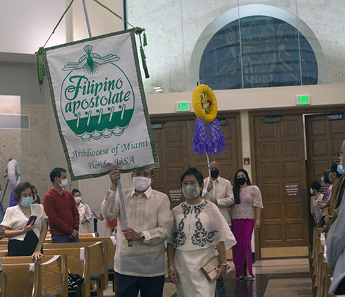 Eusie and Reggie Velasco carry the Filipino Apostolate banner into St. Bonaventure Church in Davie on the last night of the Simbang Gabi novena, Dec. 23, 2021.