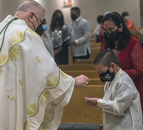 Gunnar Herman, 9, receives Communion from Archbishop Thomas Wenski on the final night of Simbang Gabi, a nine-night novena of Masses anticipating Christmas, on Dec. 23, 2021 at St. Bonaventure Church in Davie.