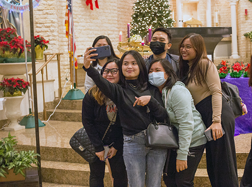 A group of young Filipino-Americans takes a selfie near the altar after the final Mass of the Simbang Gabi novena, Dec. 23, 2021 at St. Bonaventure Church in Davie.