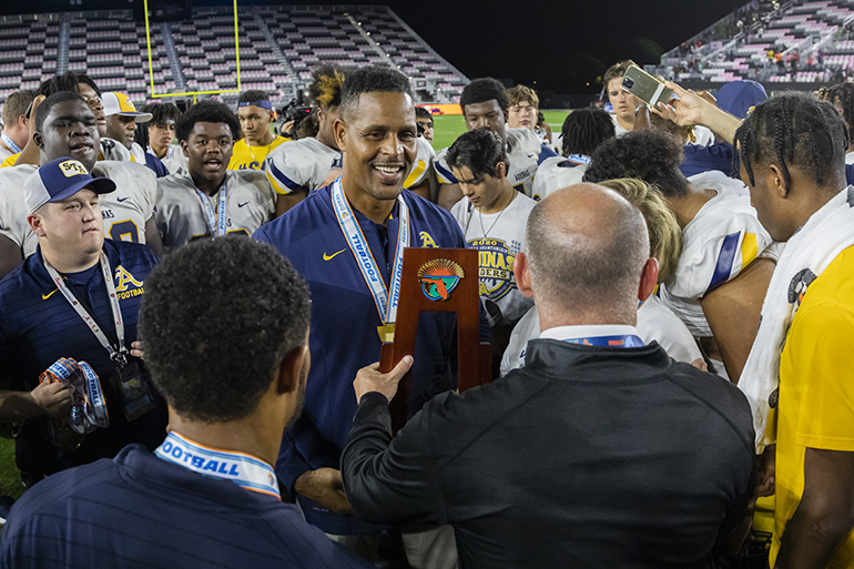 St. Thomas Aquinas athletic director Twan Russell receives the Class 7A State championship trophy from FHSAA director of athletics Robbie Lindeman. Aquinas defeated Tampa Bay Tech, 42 to 14 at DRV PNK Stadium in Fort Lauderdale, Dec. 17, 2021.