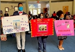 Student Council Team candidates show campaign posters during Catholic School Week at the Marian Center School. From left are Octavis Williams, president; Jacqueline Liu, vice president, and Treasure Smith, secretary.