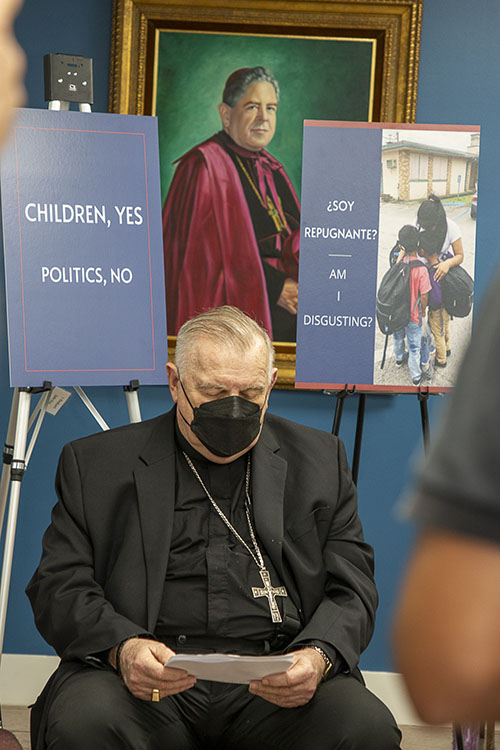 Durante una conferencia de prensa el 10 de febrero de 2022 en las oficinas del Centro Pastoral, el primer arzobispo de Miami, Coleman Carroll, parece mirar a su sucesor, el Arzobispo Thomas Wenski, mientras los carteles proclaman la determinación de la Arquidiócesis de Miami de seguir acogiendo a los menores no acompañados, al igual que el arzobispo Carroll acogió a los niños Pedro Pan en la década de 1960.