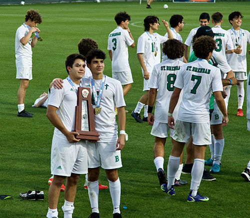 Brothers Hiroshi and Hazime Arai pose with the state championship trophy after helping St. Brendan High School's boys soccer team win the school's first ever title in that sport, with a 1-0 defeat of Orlando's Bishop Moore, Feb. 24, 2022.